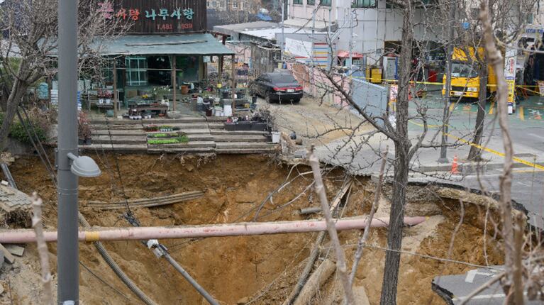 El impacto de la calle colapsada también provocó la rotura de un caño de agua, lo que generó una gran fuga en la zona. (Foto: AFP/Anthony Wallace)